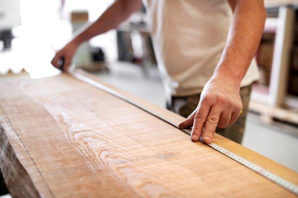 Carpenter,Using,A,Measuring,Tape,In,A,Workshop,To,Measure